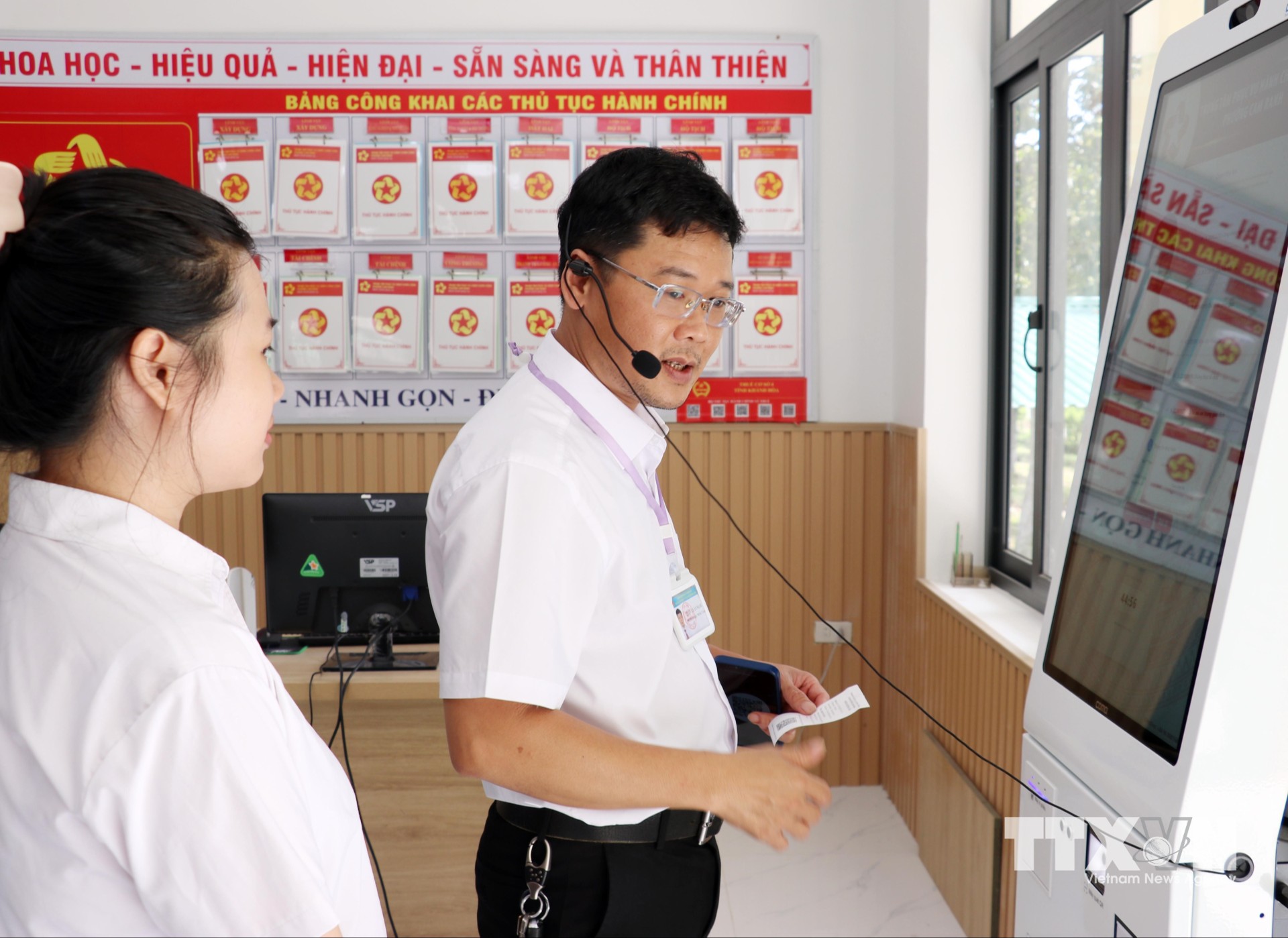 Lãnh đạo Trung tâm Phục vụ hành chính công phường Cam Ranh hướng dẫn nhân viên tư vấn sử dụng công nghệ hỗ trợ giải quyết thủ tục hành chính cho người dân. (Ảnh: Công Thử/TTXVN)